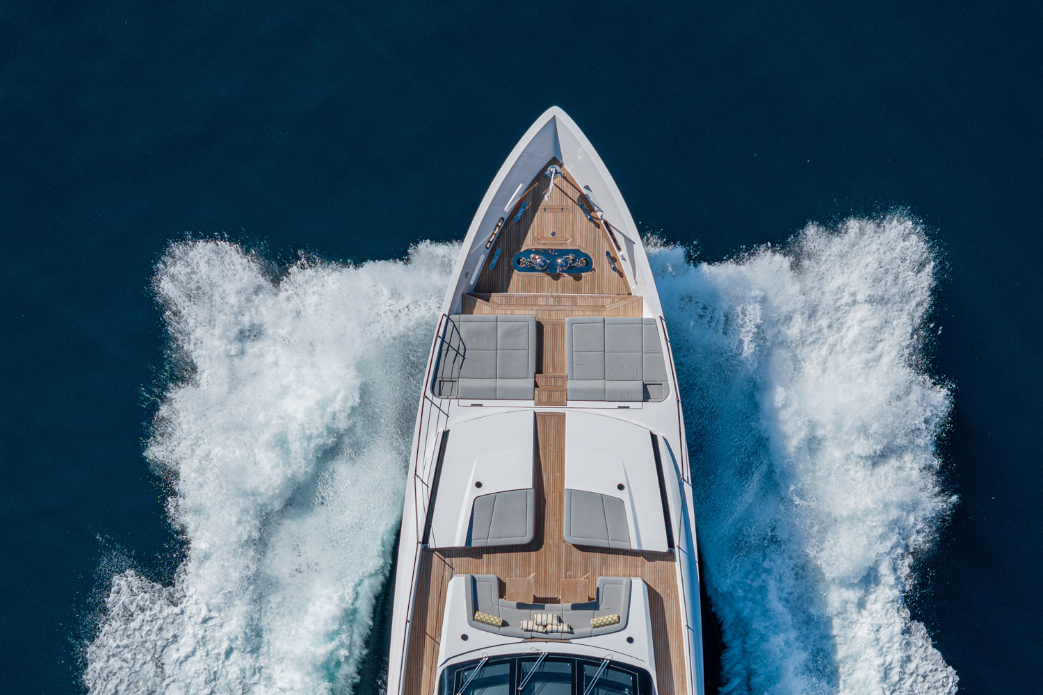 Aerial photograph of a yacht cruising near Cannes, with the Mediterranean coastline in the background.