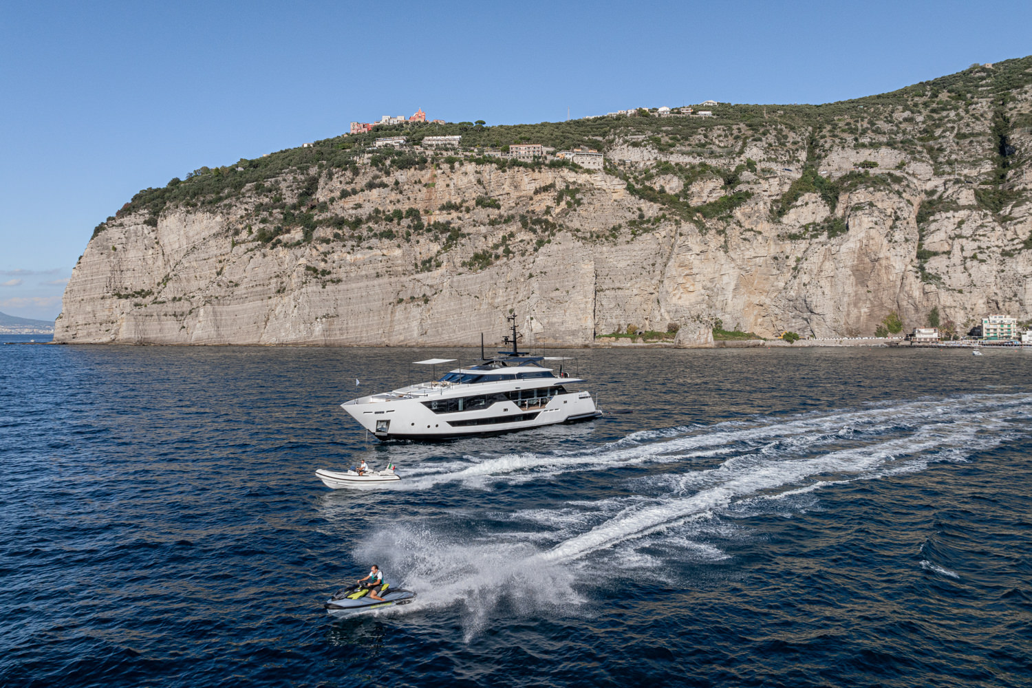Aerial view of a yacht cruising near Saint-Tropez, with the beautiful Mediterranean coastline in the background.