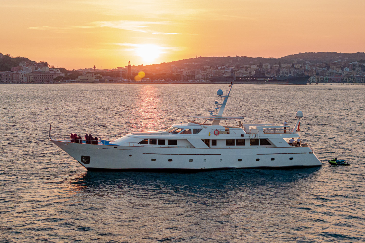 Aerial view of a yacht cruising near Monaco, with the Mediterranean coastline and clear waters below.