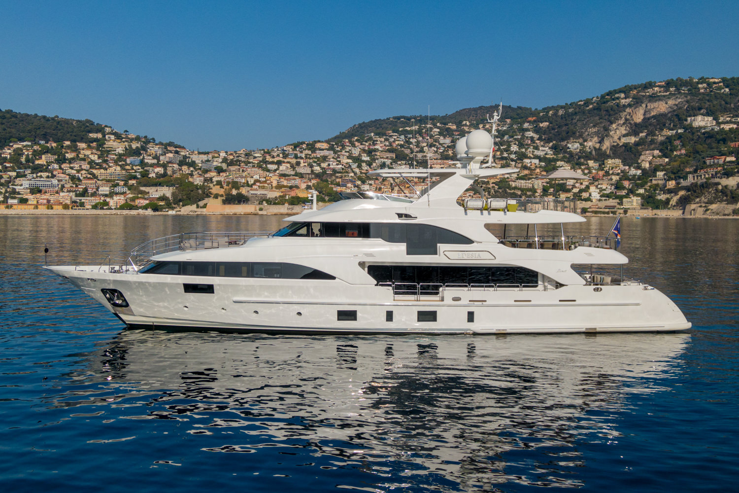 Aerial view of a yacht cruising near Saint-Tropez, with the Mediterranean coastline in the background.
