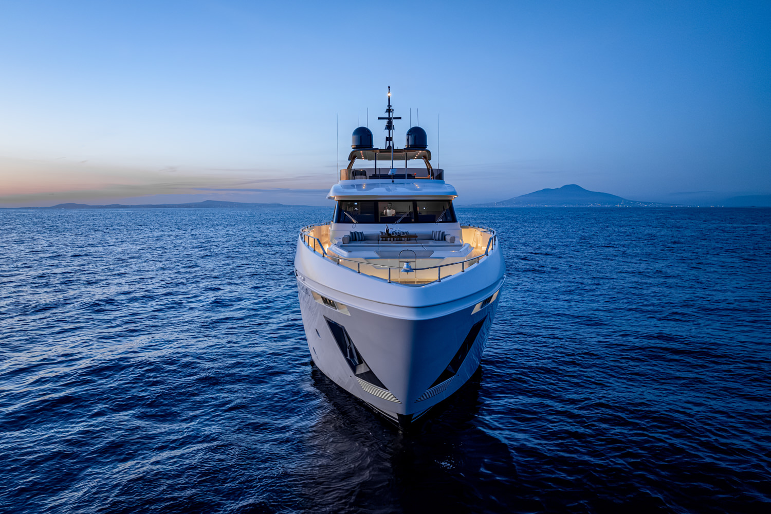 Aerial view of a yacht sailing near the coast of Cannes, with clear blue waters and scenic hills in the background.