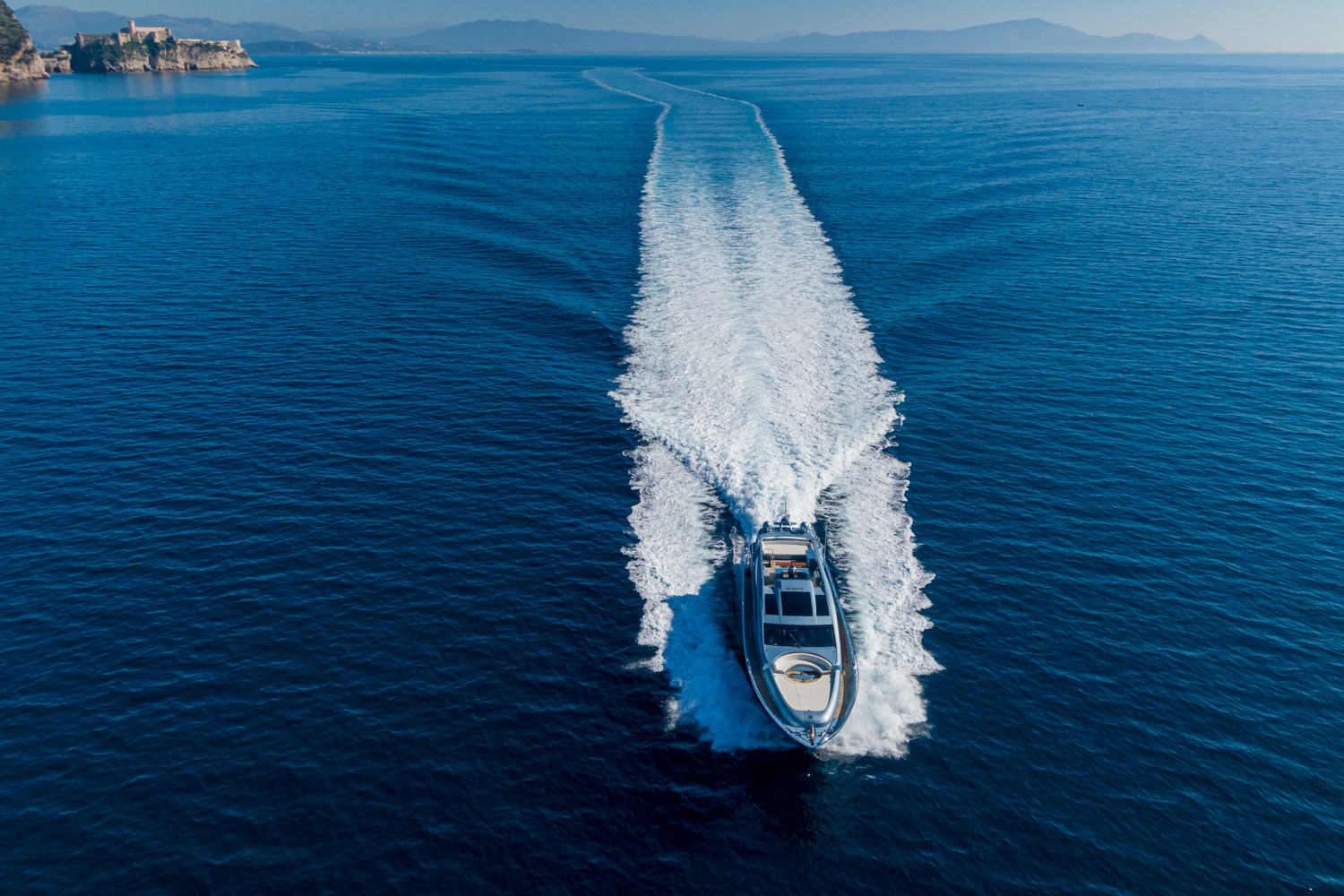 Aerial photograph of a yacht cruising near Cannes, with the beautiful Mediterranean coastline in the background.