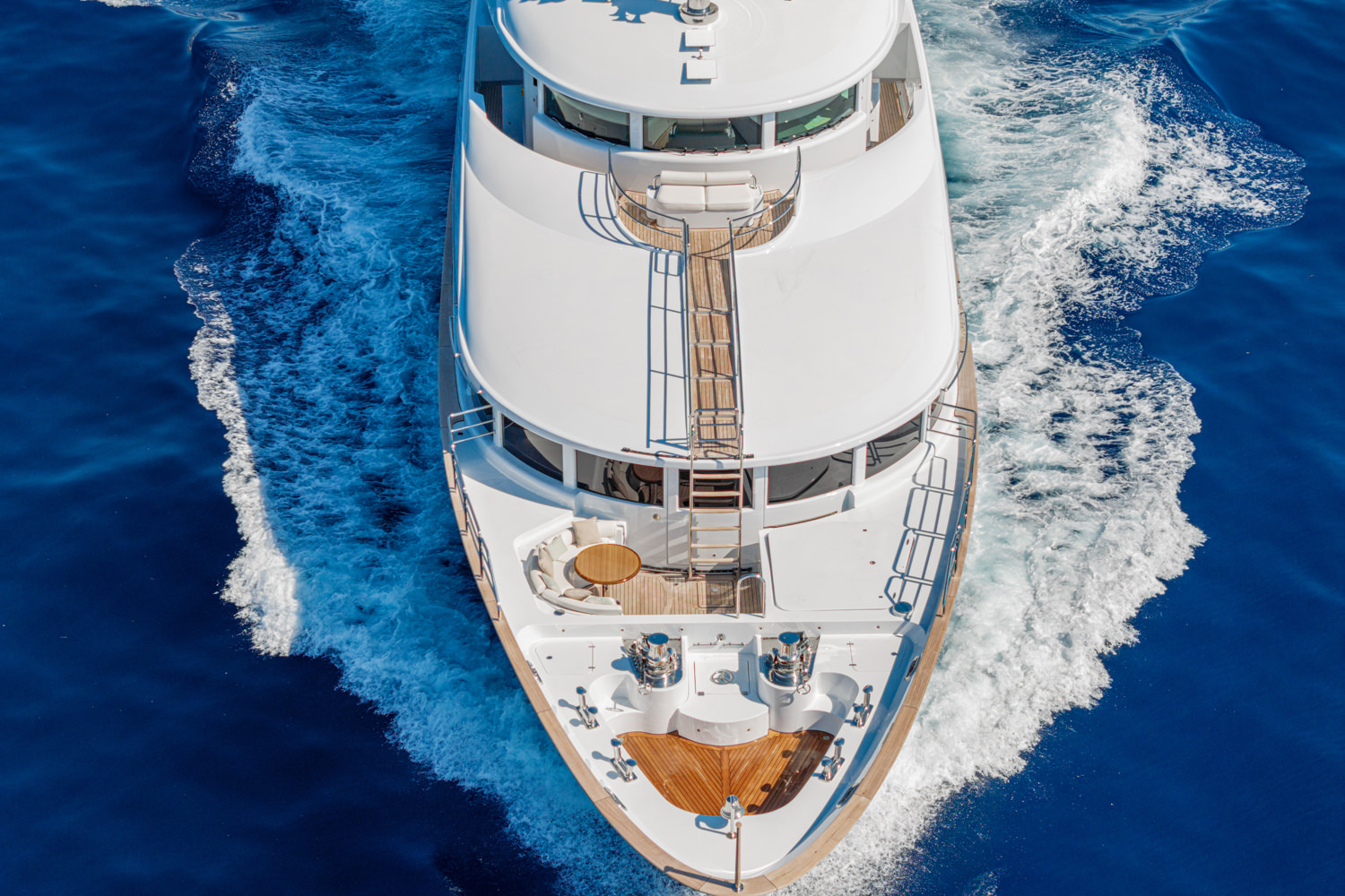 Aerial view of a yacht navigating through the Mediterranean waters near Cannes, with a scenic coastline in the background.