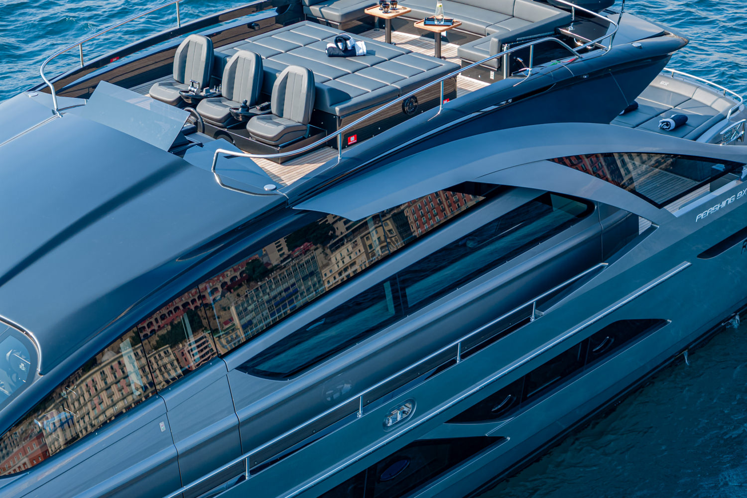 Aerial photograph of a yacht cruising near Monaco, with the Mediterranean Sea and coastline in the background.