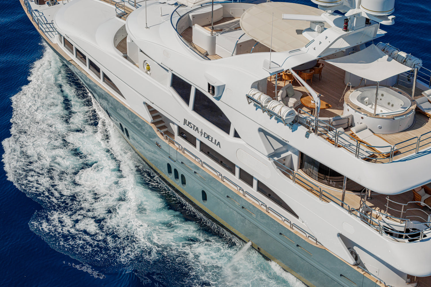 Aerial photograph of a luxury yacht cruising near Saint-Tropez, with the scenic French Riviera coastline in the background.