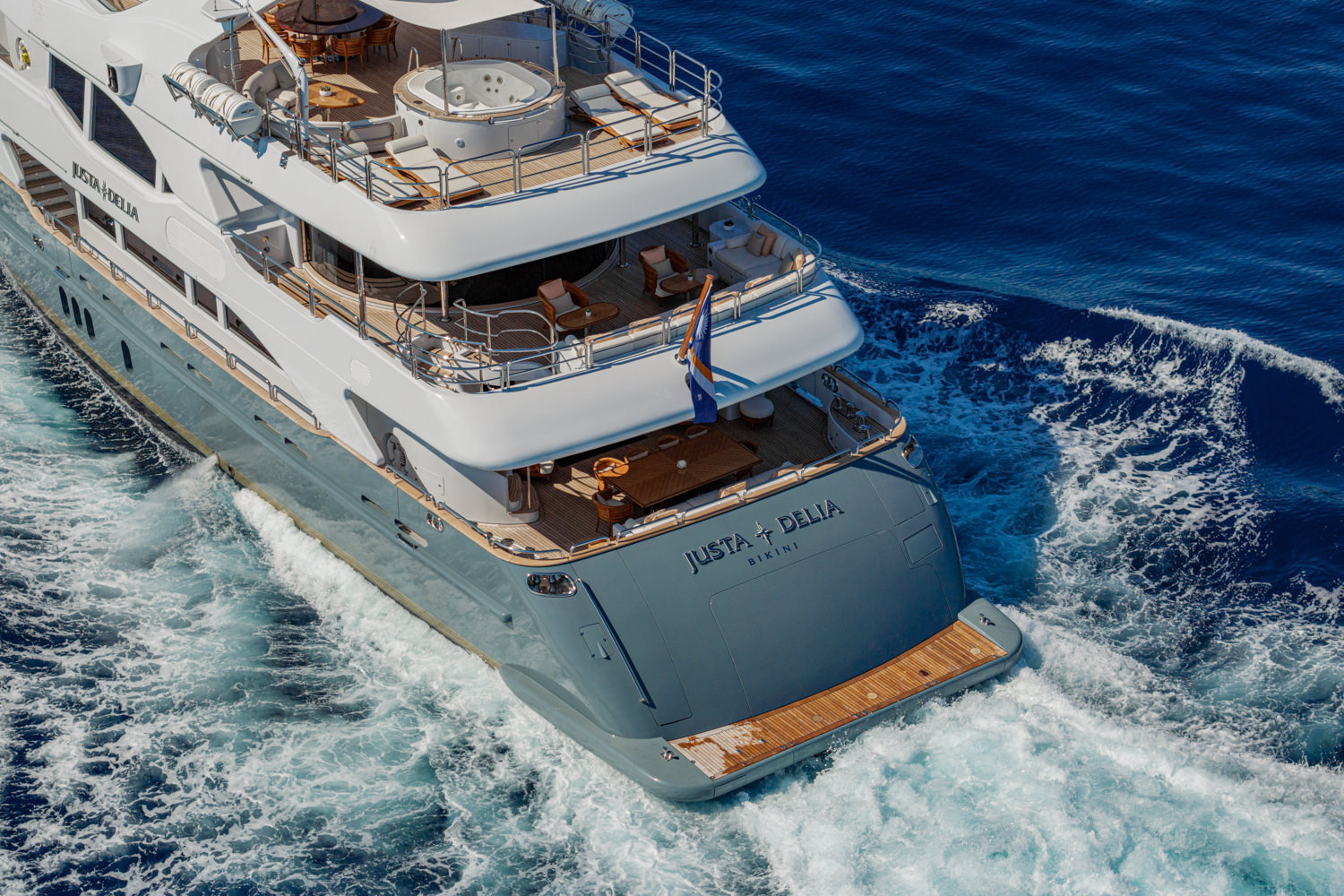 Aerial view of a luxury yacht cruising near Nice, with the French Riviera coastline in the background.