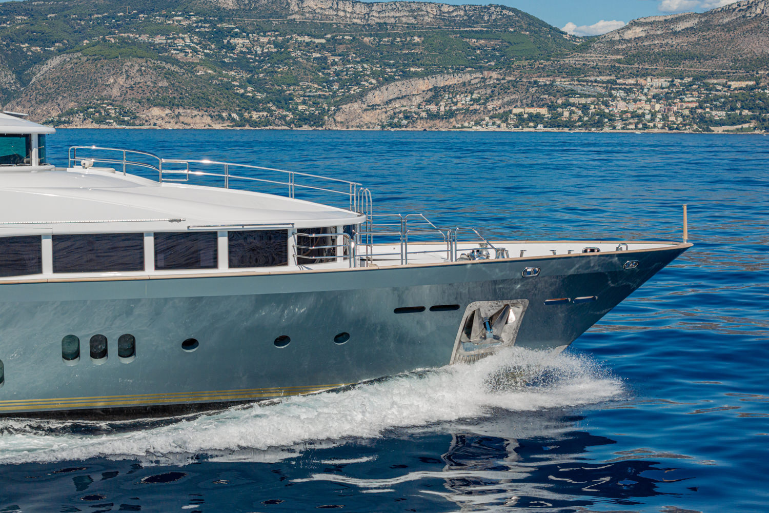 Drone photograph of a luxury yacht cruising near Antibes, with the stunning French Riviera coastline in the background.