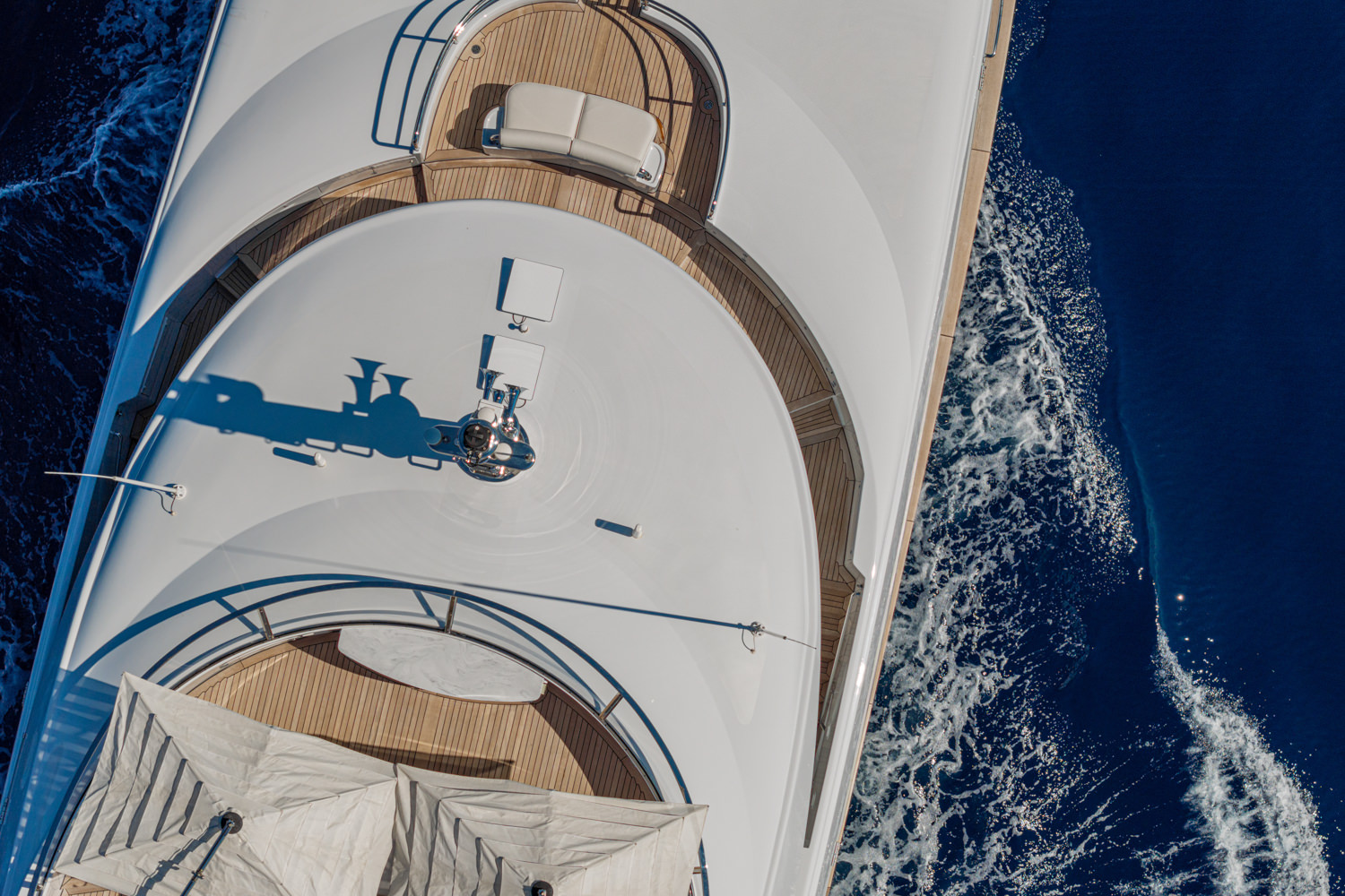 Aerial photograph of a luxury yacht cruising near Monaco, with the Mediterranean coastline and luxury cityscape in the background.
