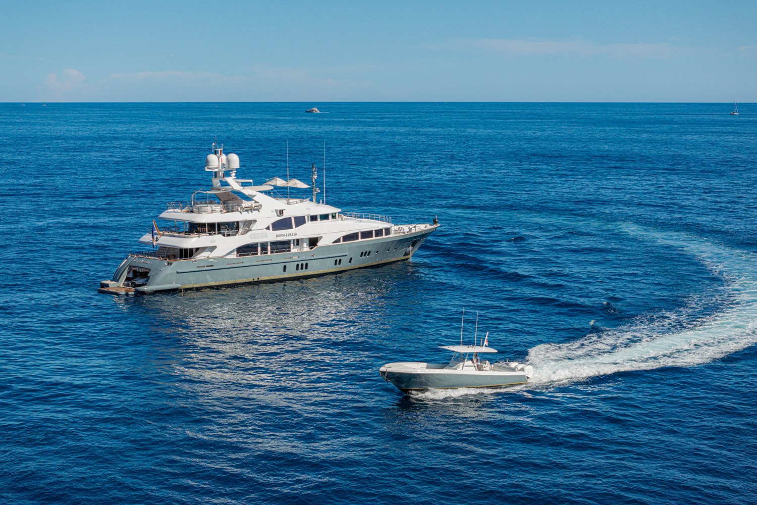 Aerial shot of a luxury yacht cruising near Saint-Tropez, with the French Riviera coastline in the background.