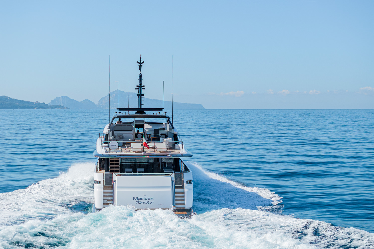 Aerial view of a yacht cruising near Antibes, with the beautiful French Riviera coastline in the background.