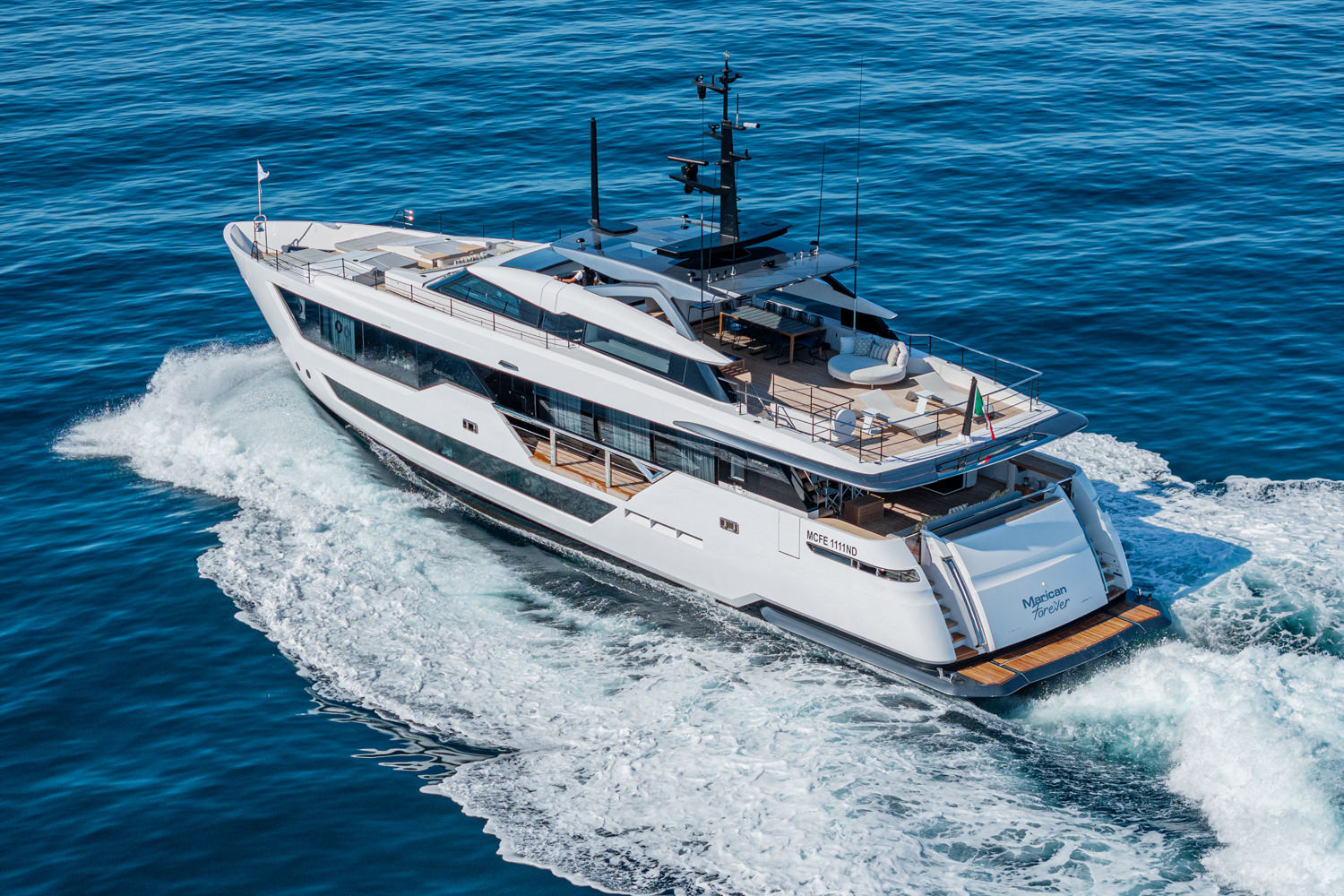 Aerial photograph of a yacht cruising near Saint-Tropez, with the stunning French Riviera coastline in the background.