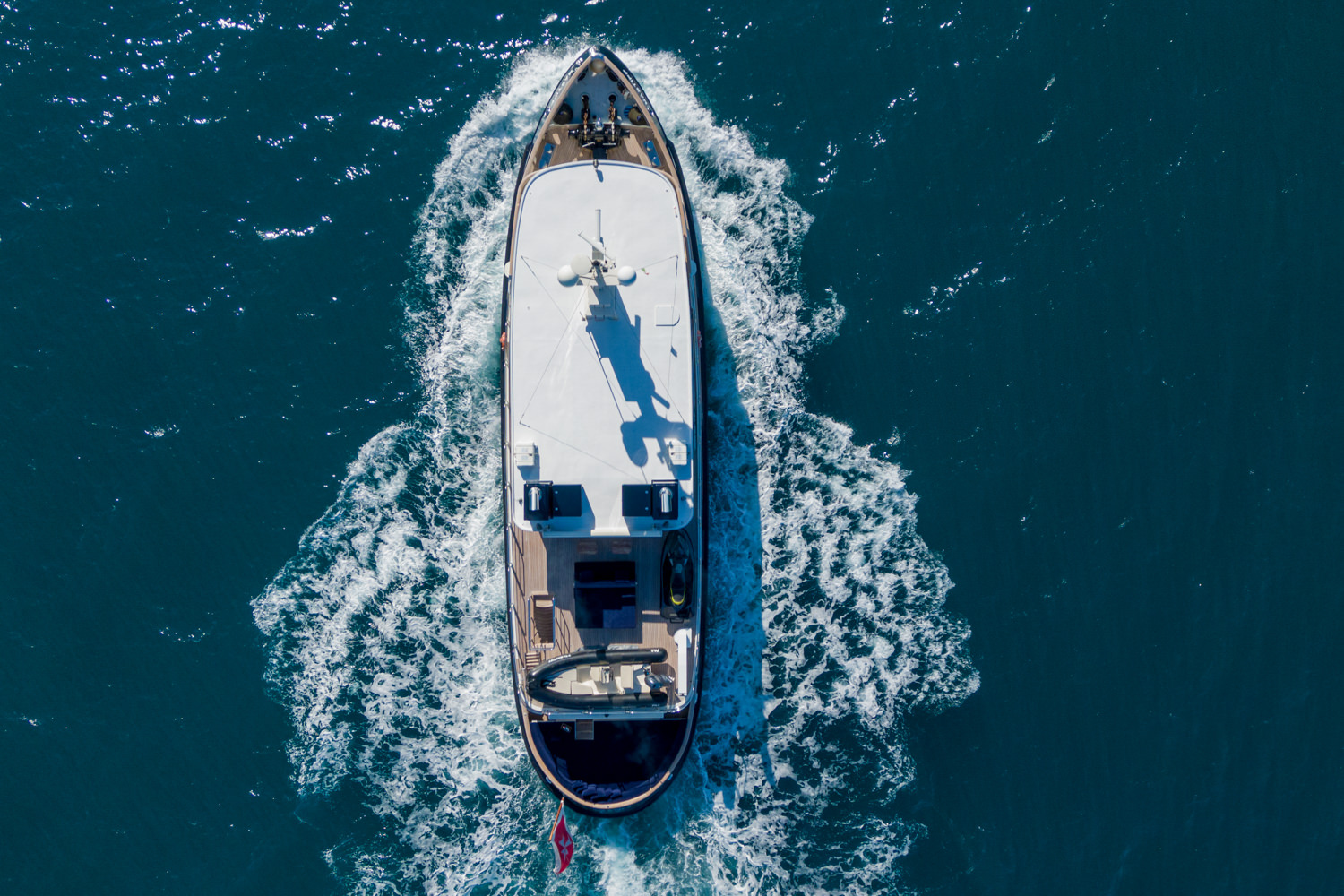 Aerial photograph of a luxury yacht cruising near Sanremo, with the Mediterranean coastline in the background.