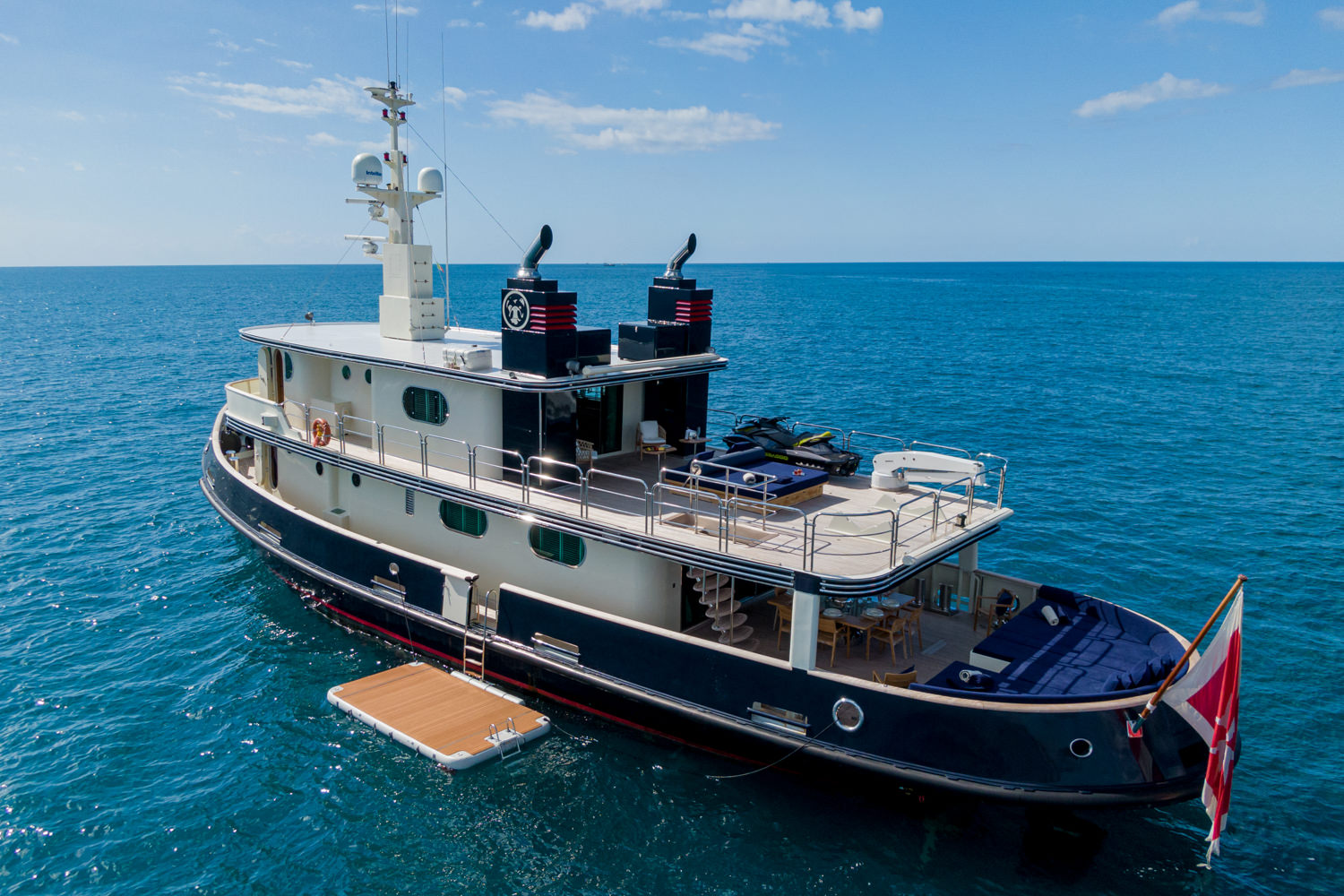 Aerial shot of a luxury yacht cruising near Livorno, with the Tuscan coastline in the background.