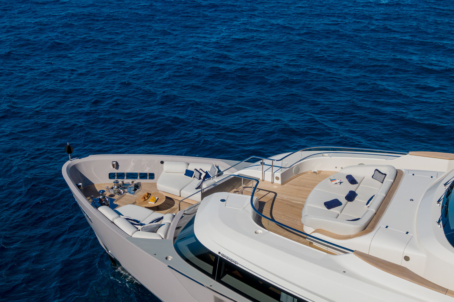 Drone image of a luxury yacht cruising near Genoa, with the Ligurian coastline in the background.