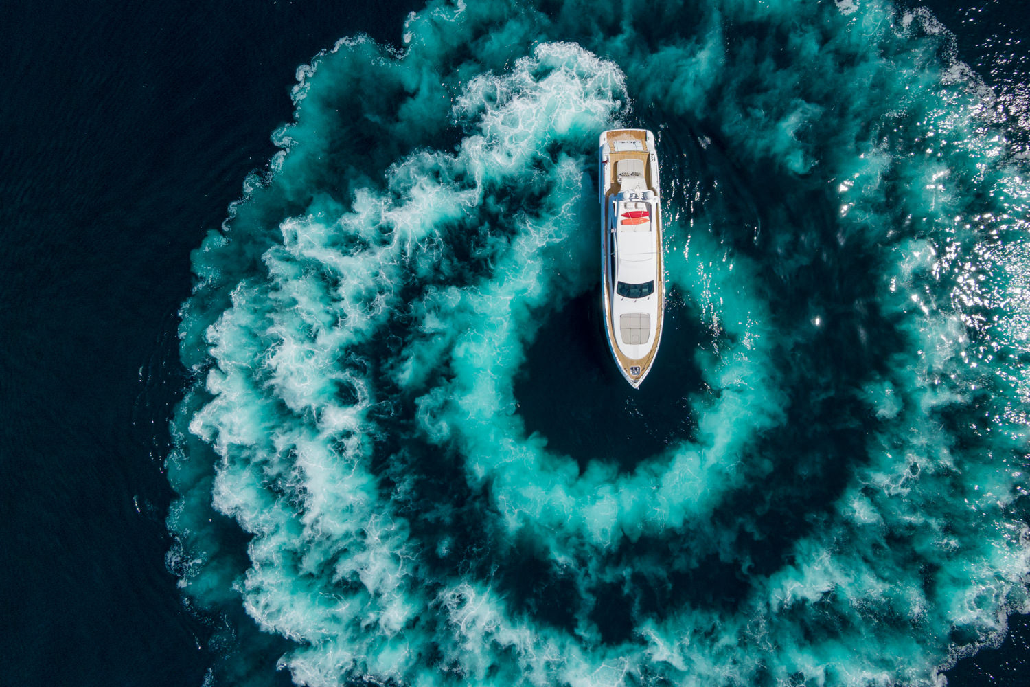 Drone shot of a luxury yacht sailing near Ventimiglia, with the Italian coastline in the background.