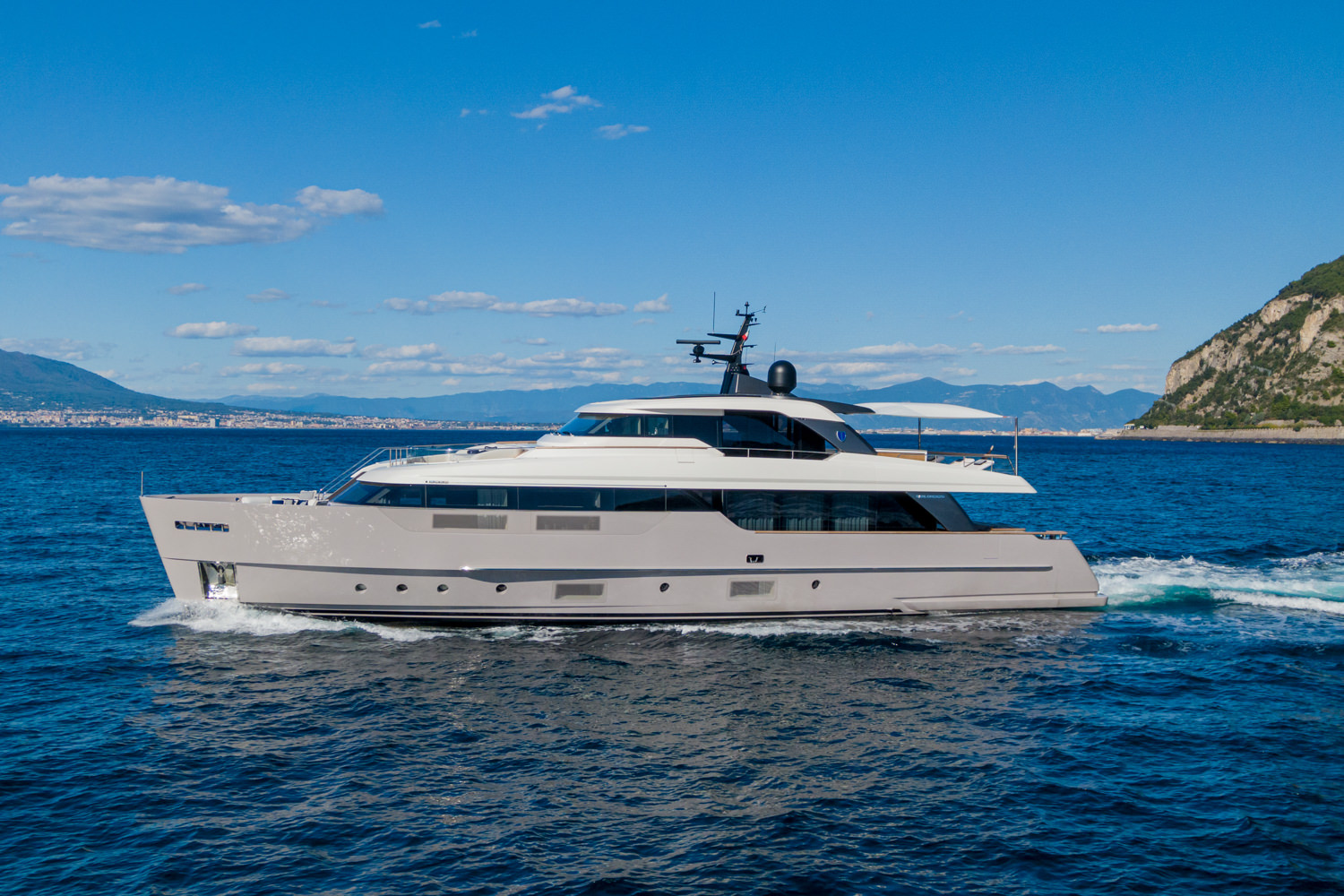 Aerial view of a luxury yacht cruising near Cannes, with the Mediterranean coastline in the background.