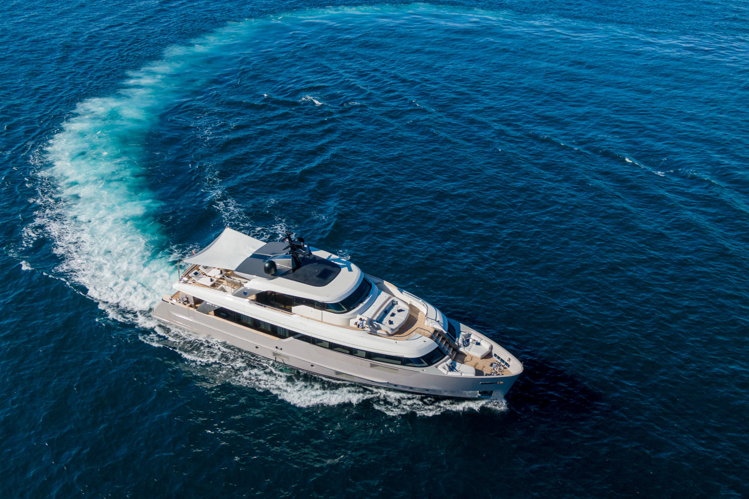 Aerial photograph of a luxury yacht cruising near Antibes, with the stunning French Riviera coastline in the background.