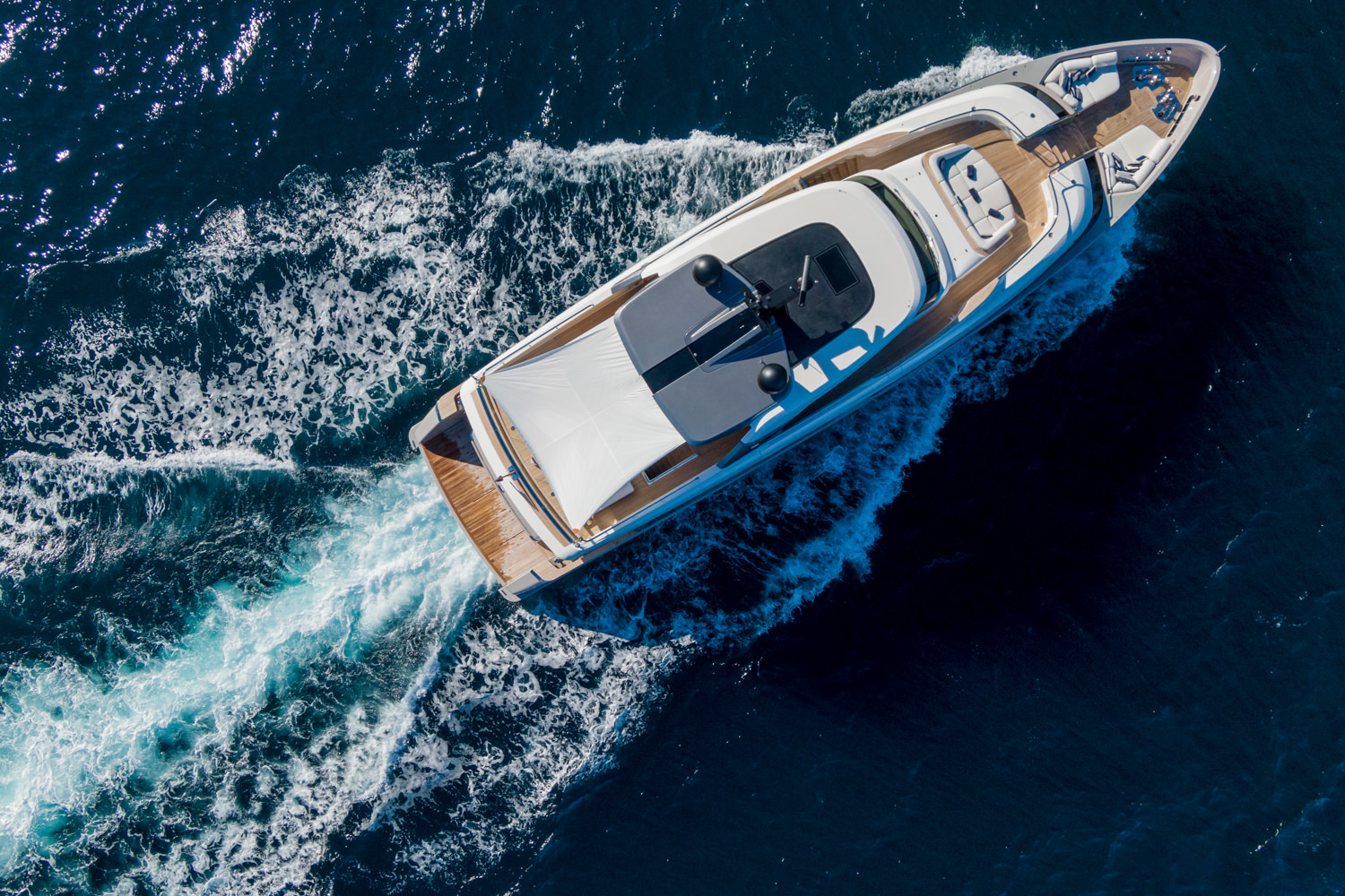 Aerial shot of a luxury yacht anchored near Naples, with the coastal landscape in the background.