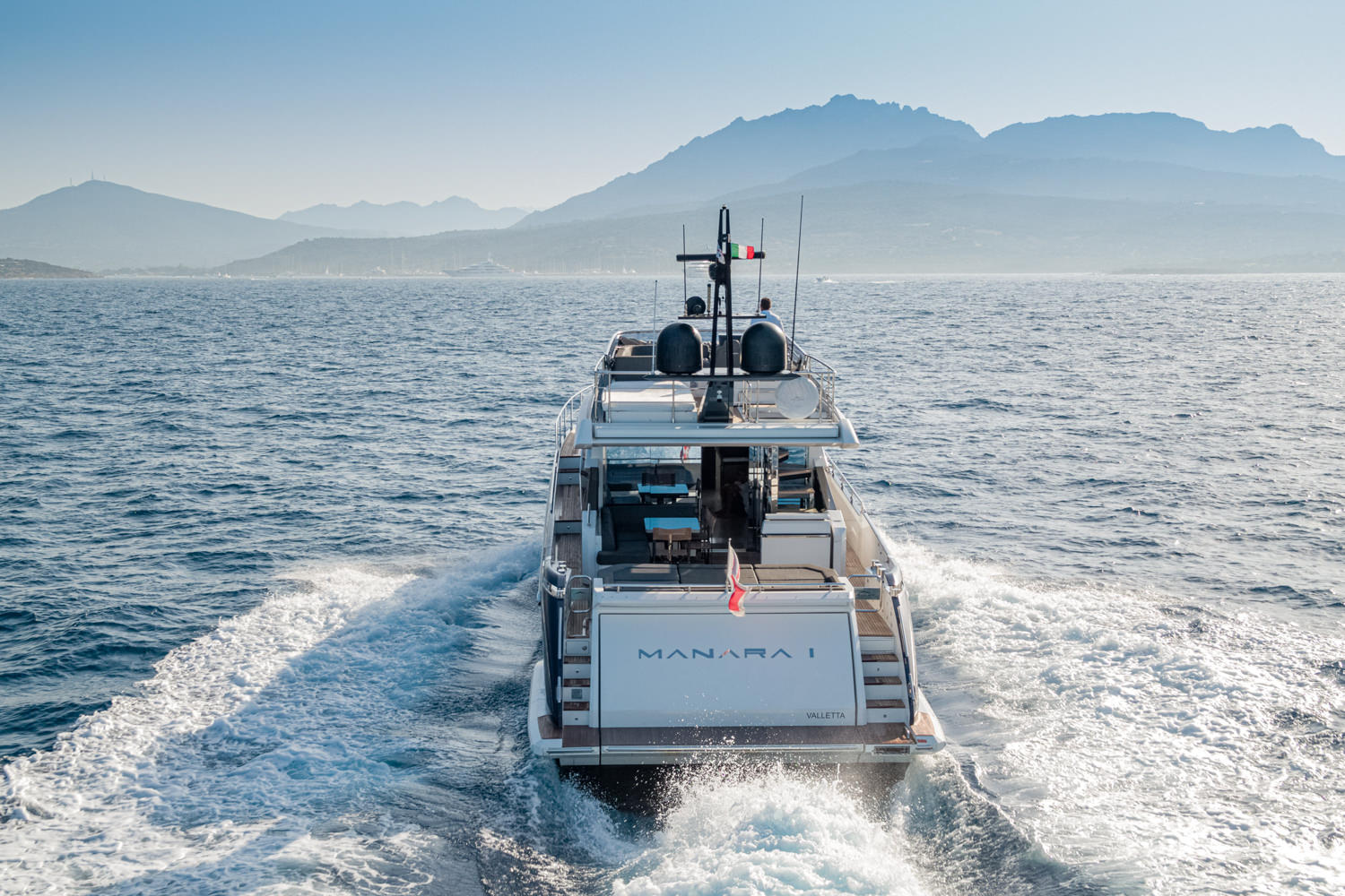 Aerial photograph of a luxury yacht cruising near Nice, with the stunning French Riviera coastline in the background.