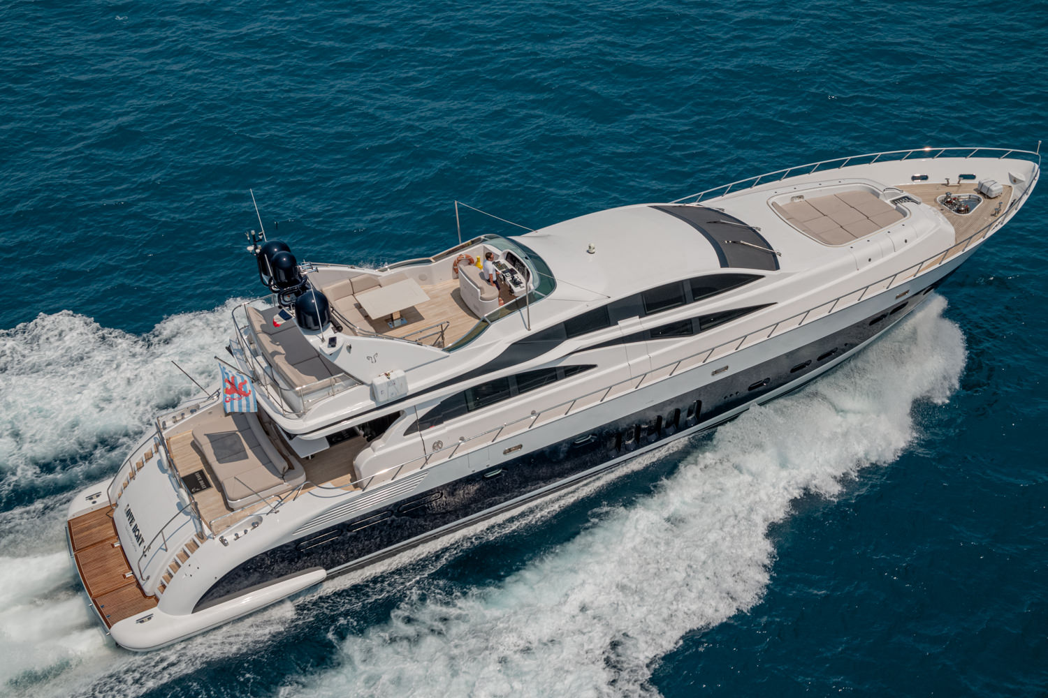 Drone image of a luxury yacht sailing near Genoa, with the Italian coastline in the background.
