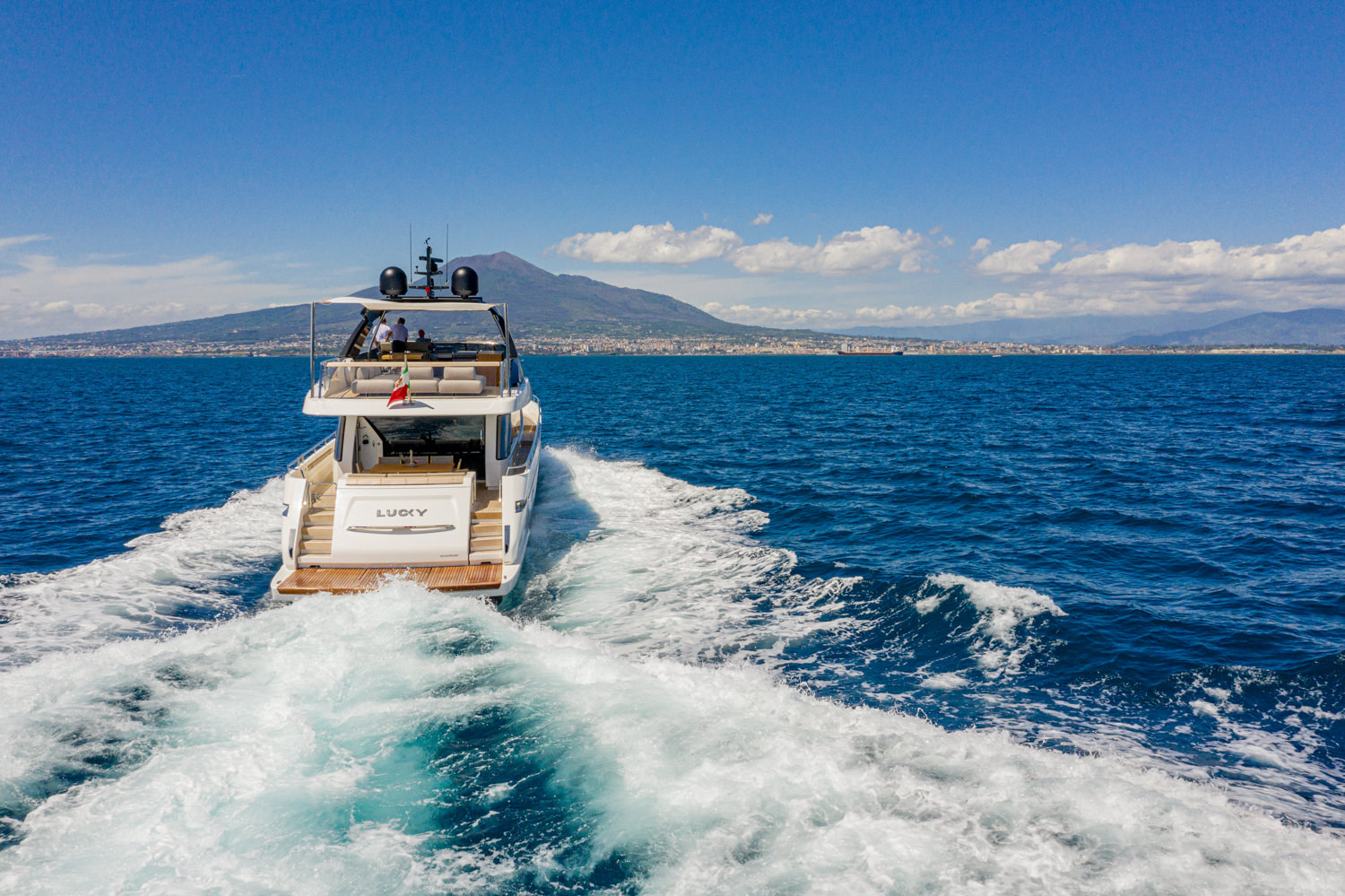 Aerial shot of a luxury yacht sailing near Cannes, with the French Riviera coastline in the background.
