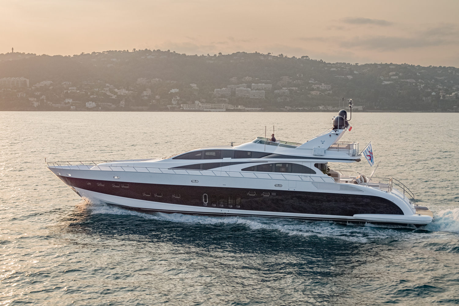 Aerial image of a luxury yacht anchored near Monaco, highlighting its sleek design against the Mediterranean coastline.