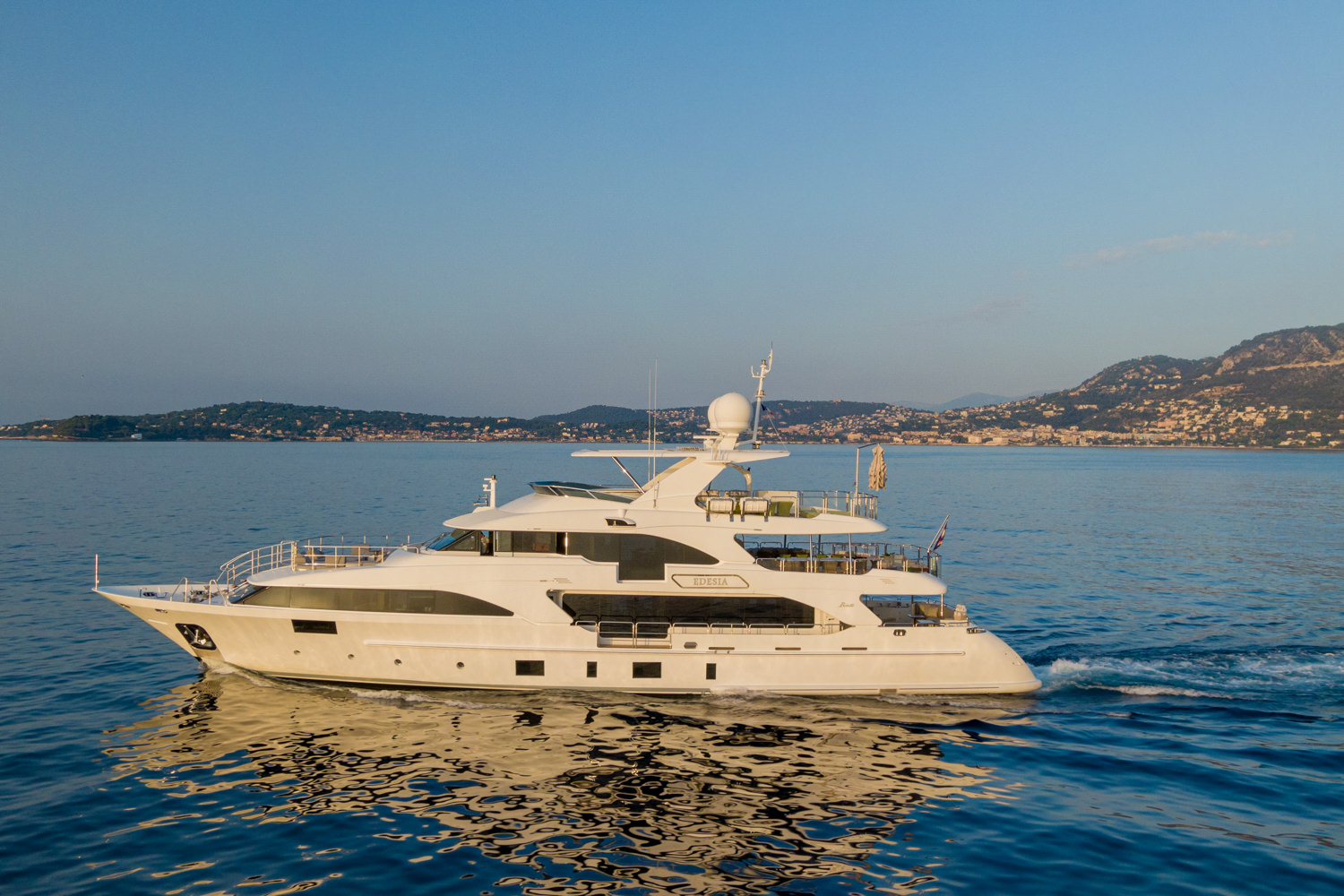 Drone shot of a luxury yacht cruising near the coast of Saint-Tropez, with the vibrant Mediterranean waters.