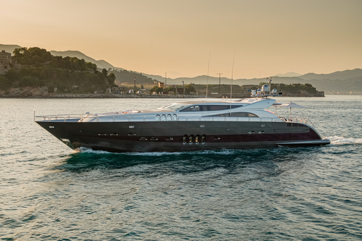 Aerial view of a luxury yacht anchored off the coast of Naples, showcasing its design against the Mediterranean backdrop.