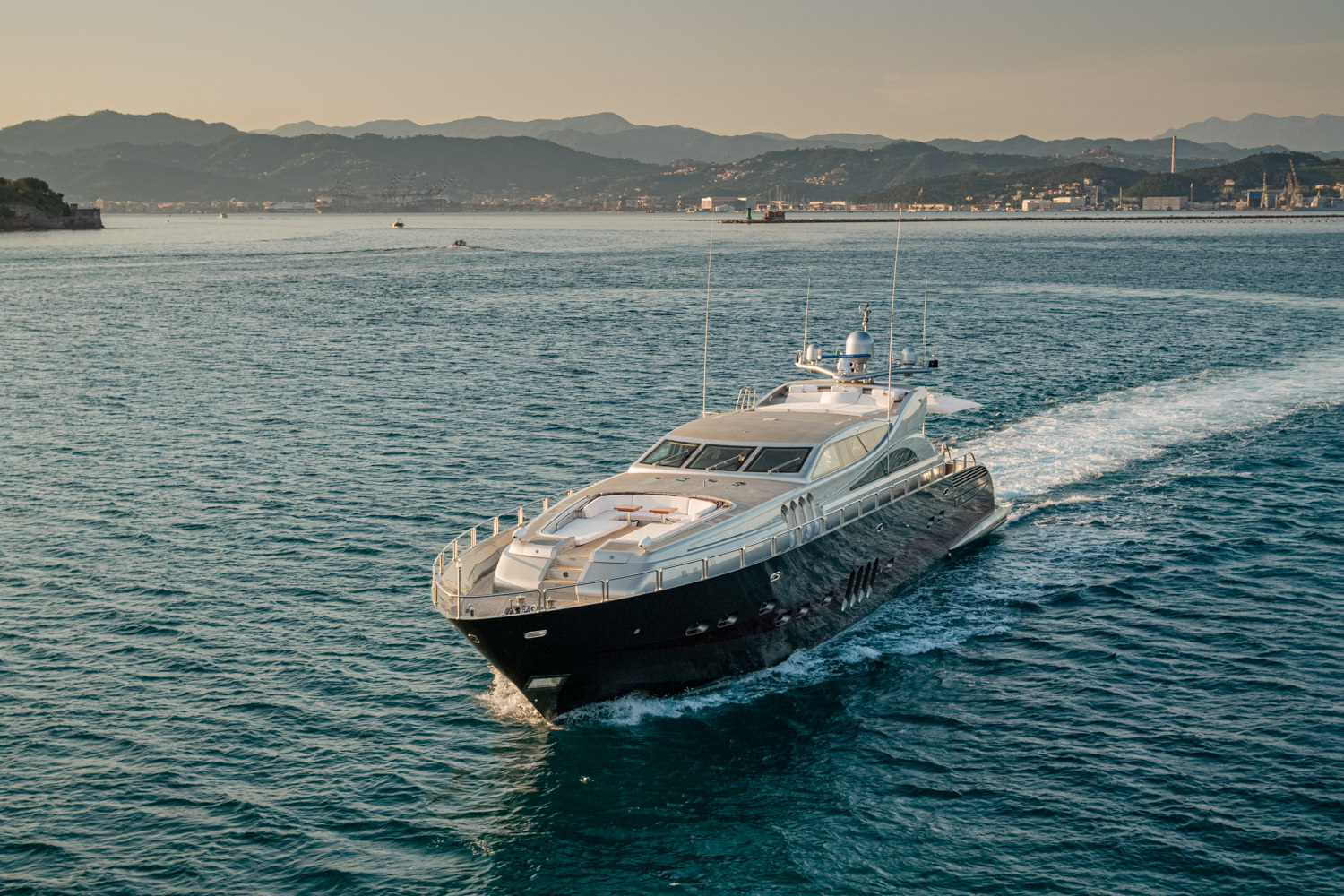 Aerial photograph of a luxury yacht cruising near Naples, with a stunning coastal view.