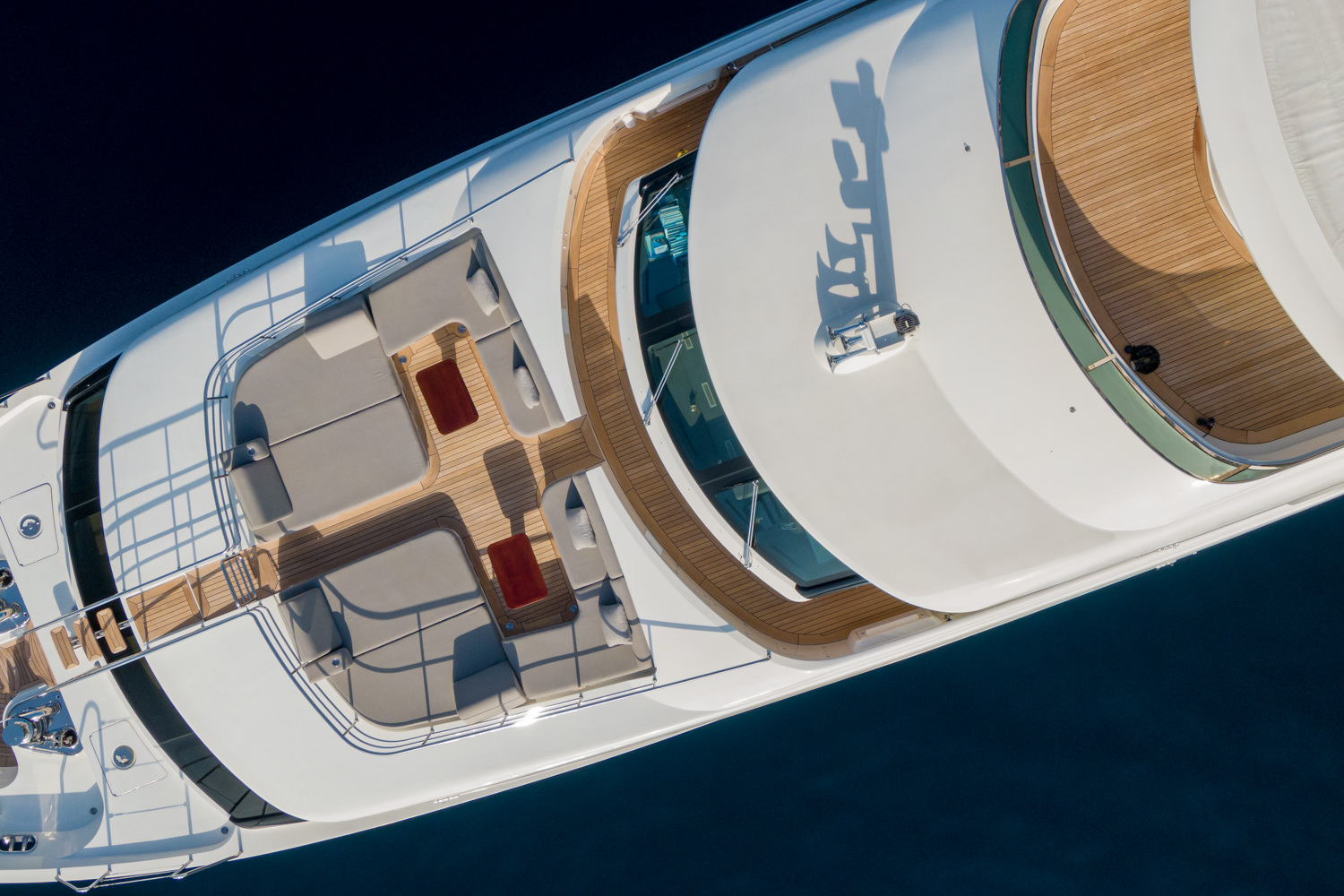Aerial view of a luxury yacht sailing near Sanremo, with the Mediterranean coast in the background.