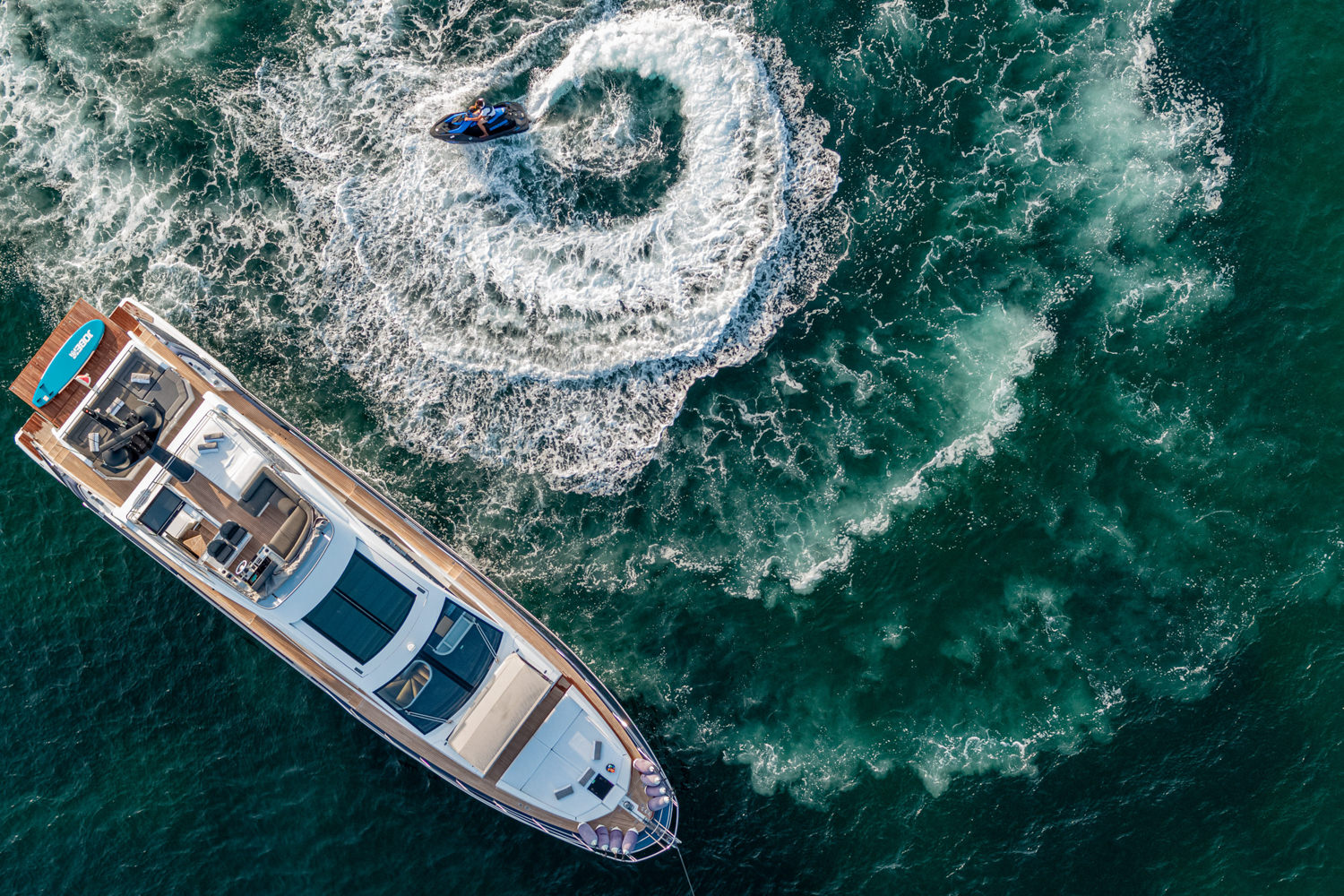 Aerial photograph of a luxury yacht cruising near Antibes, with the stunning French Riviera coastline in the background.