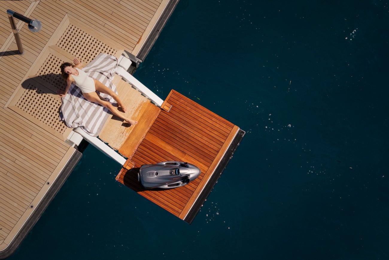 Vue plongeante sur la plateforme de bain d'un yacht, avec une personne prenant le soleil et des équipements nautiques.