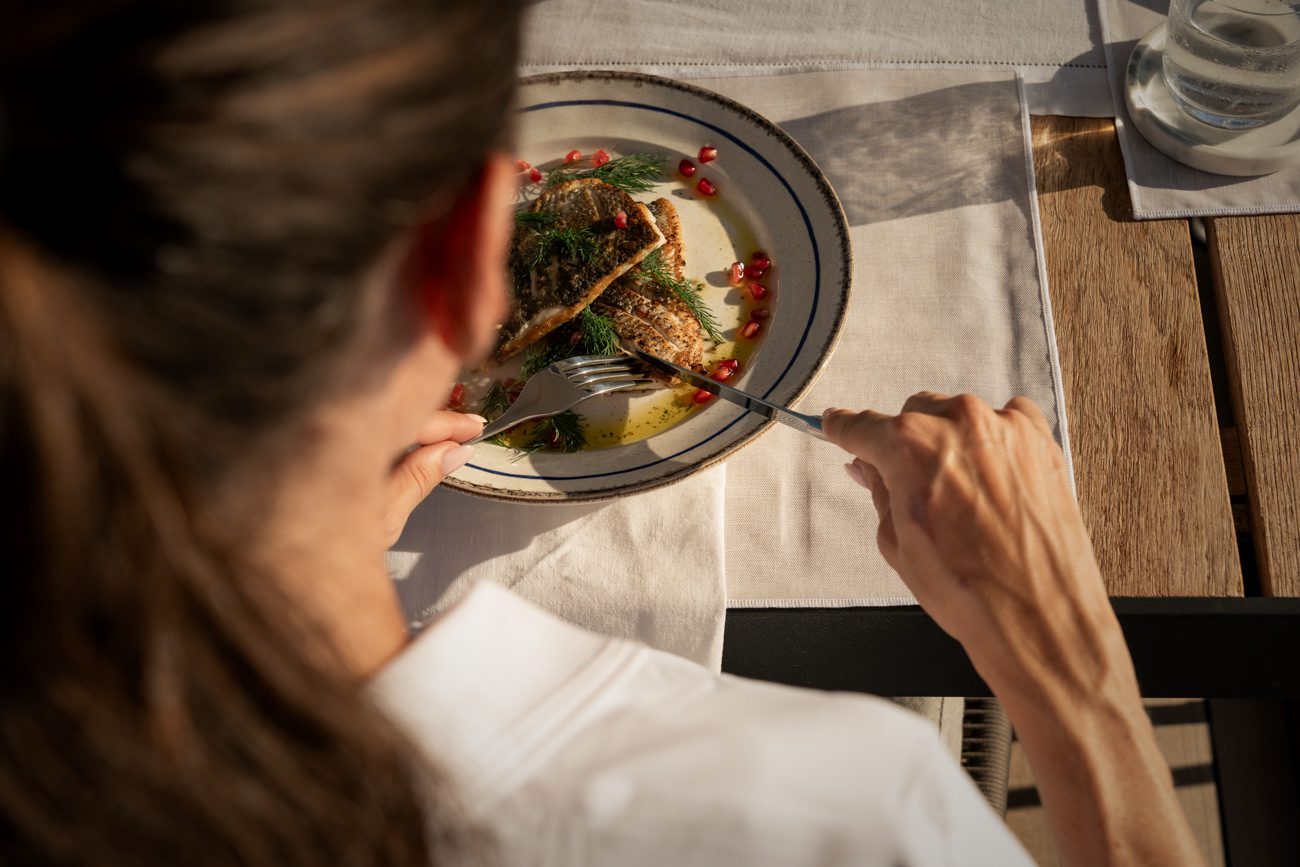 A guest enjoying a gourmet meal served at the table aboard a luxury yacht.